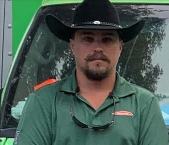 Male with Dark Facial Hair and black cowboy hat in front of green truck 