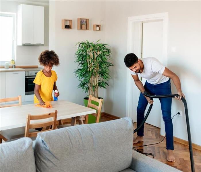 Man and child cleaning living room area together 