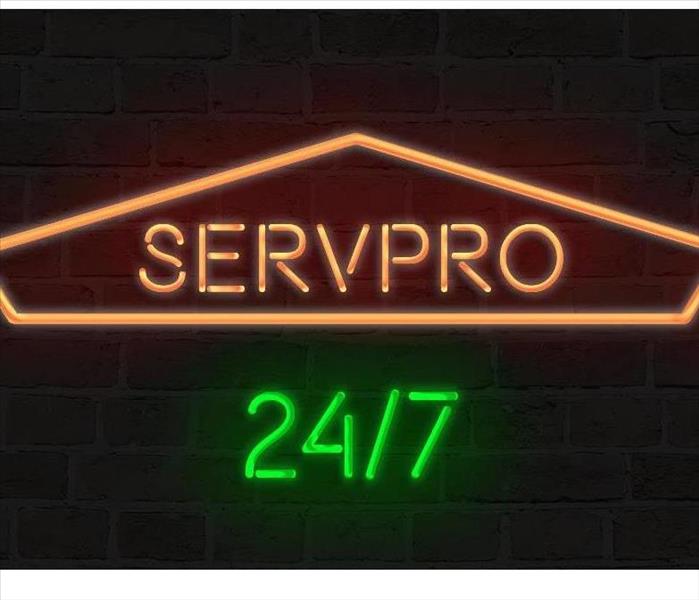 Orange and Green neon sign that reads SERVPRO 24/7